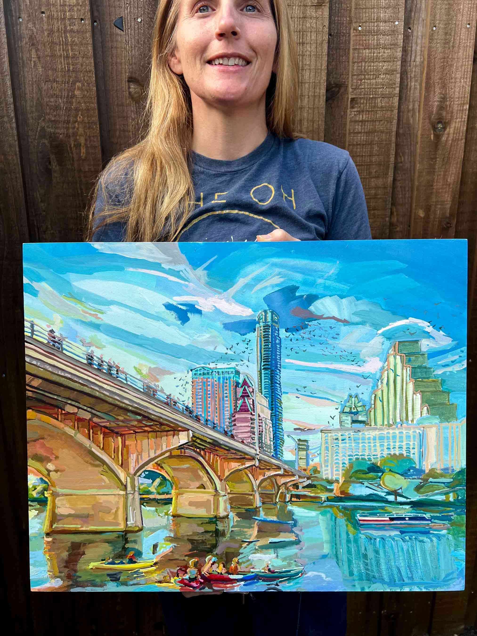 Austin painting of downtown at Congress Bridge and Lady Bird Lake with artist holding gouache painting