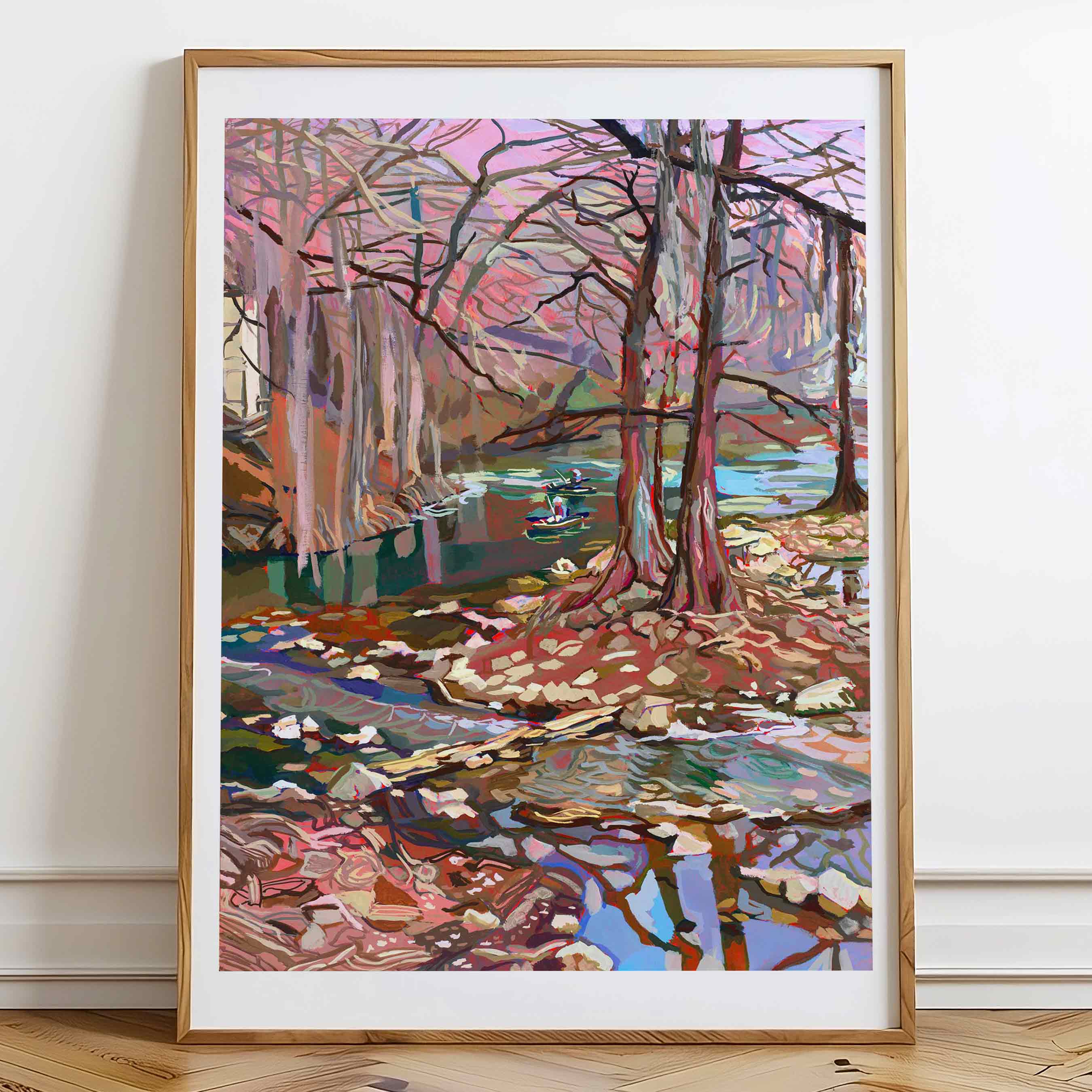 Guadalupe River painting of a landscape with Cypress trees and water on a wall in a large frame on the floor.