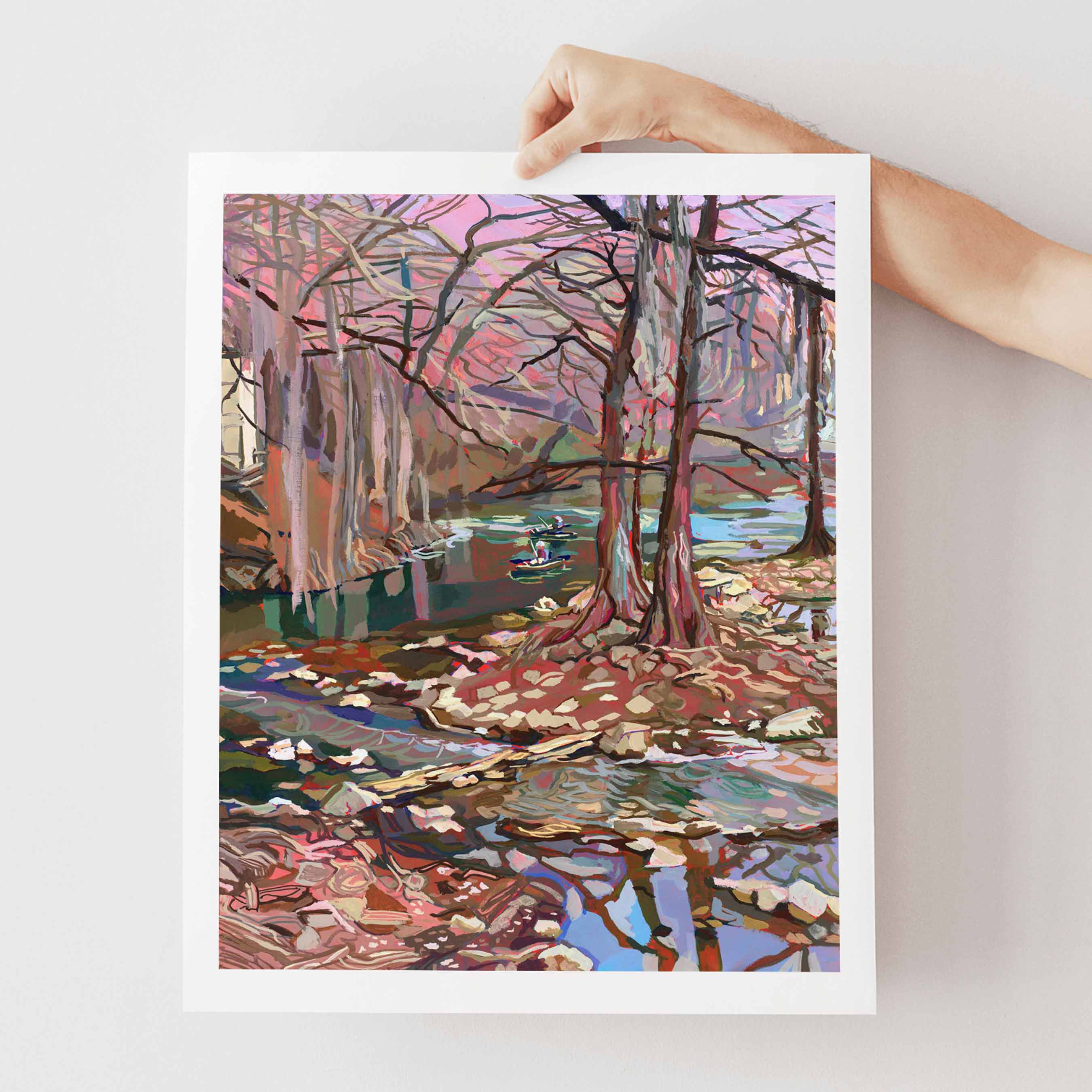 Art print of a colorful river and forest scene in Texas Hill Country with cypress trees held by a hand on a light gray background